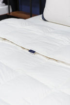 White quilted comforter on a neatly made bed with pillow, bedding for mattress