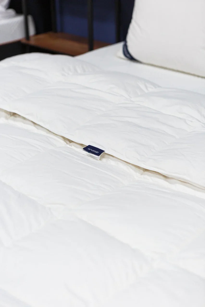 White fluffy comforter on a neatly made bed, close-up of soft bedding in bedroom.