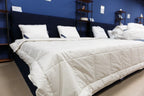 Modern bedroom with a white mattress and pillows on a bed, blue wall background
