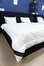 White quilted mattress topper on a modern bed with pillows in a stylish bedroom