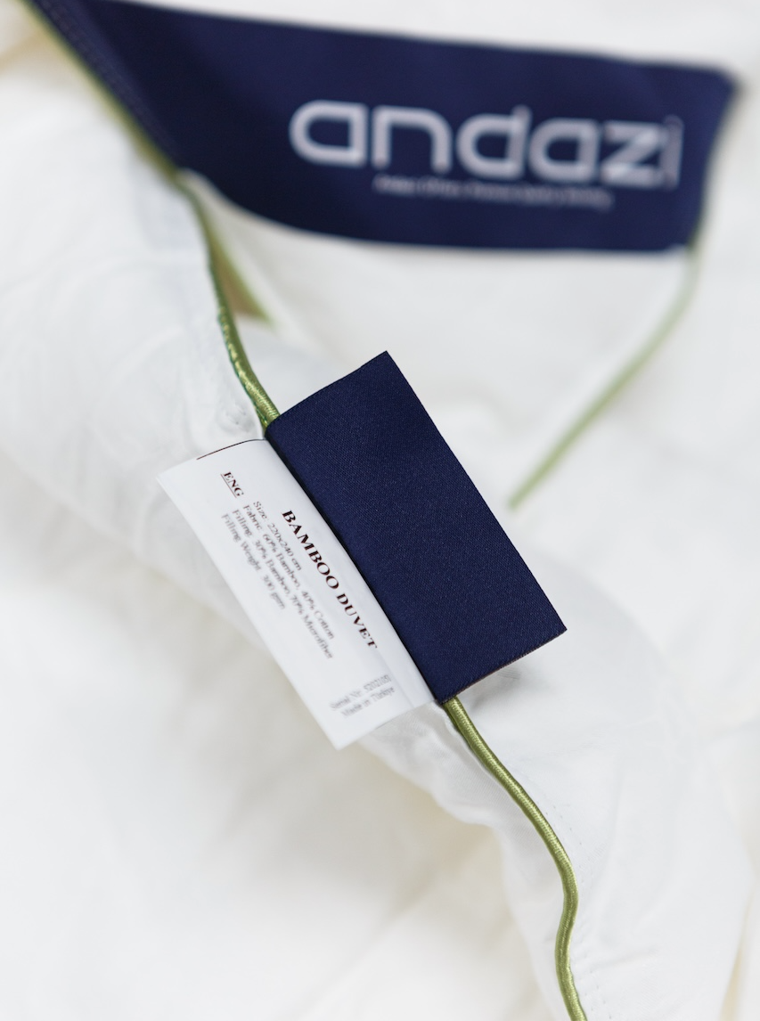 Close-up of bamboo duvet with fabric label and green piping on white bedding