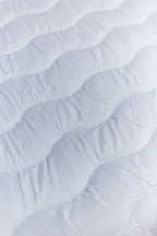 Close-up of white quilted mattress surface with wavy stitching pattern