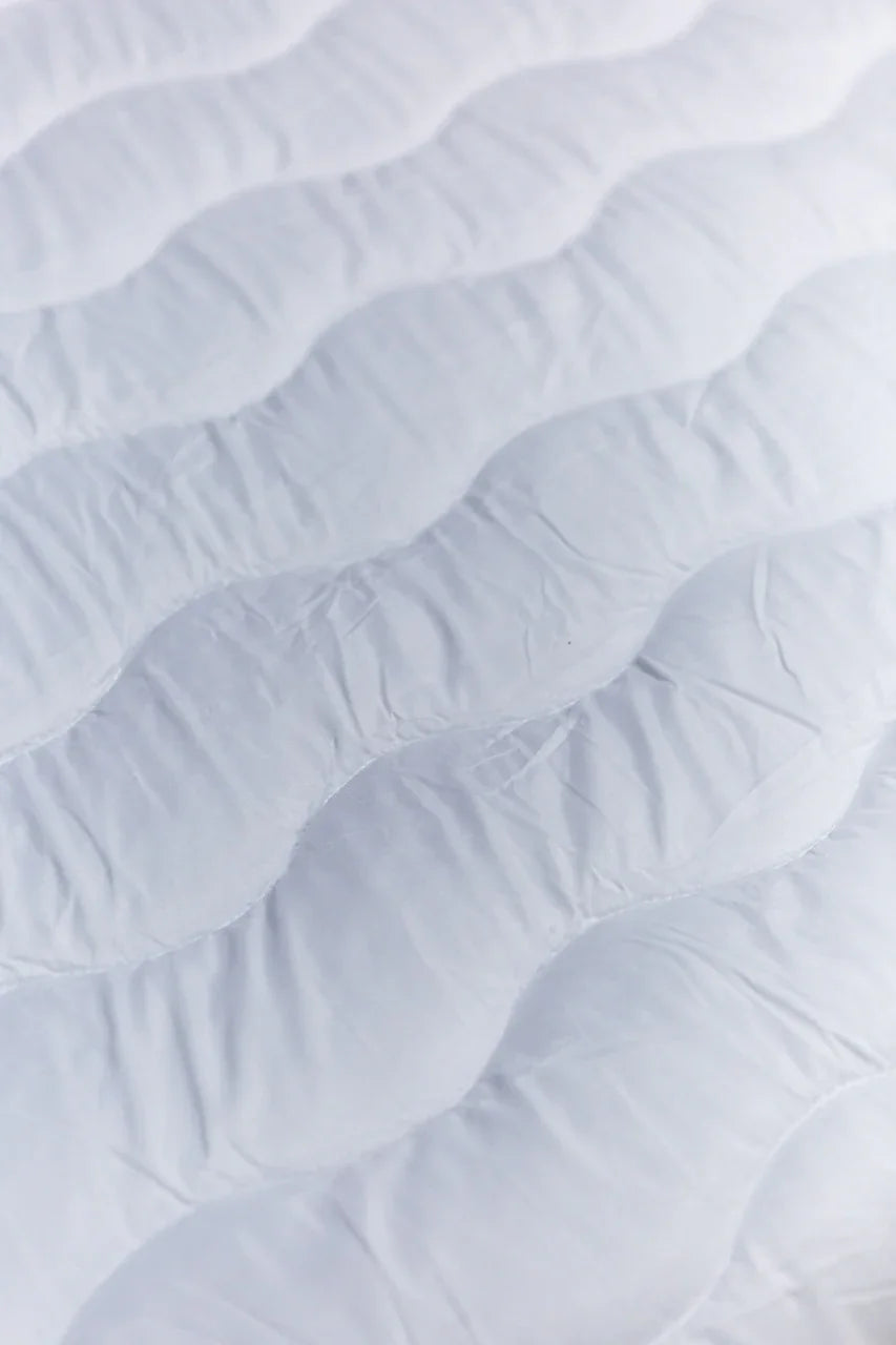 Close-up of a white quilted mattress surface with wavy stitching texture
