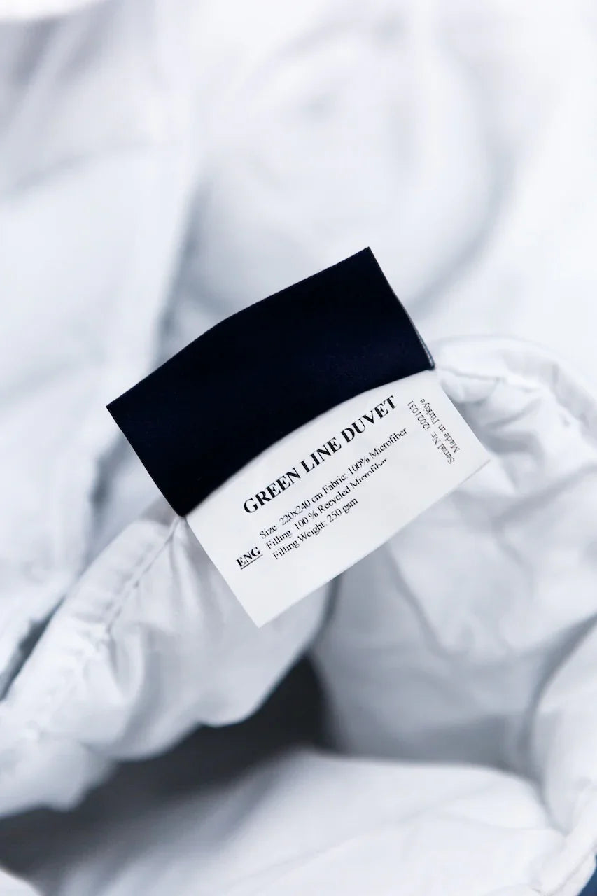 Close-up of a Green Line duvet tag on white microfiber bedding