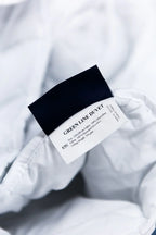 Close-up of a Green Line duvet tag on white microfiber bedding
