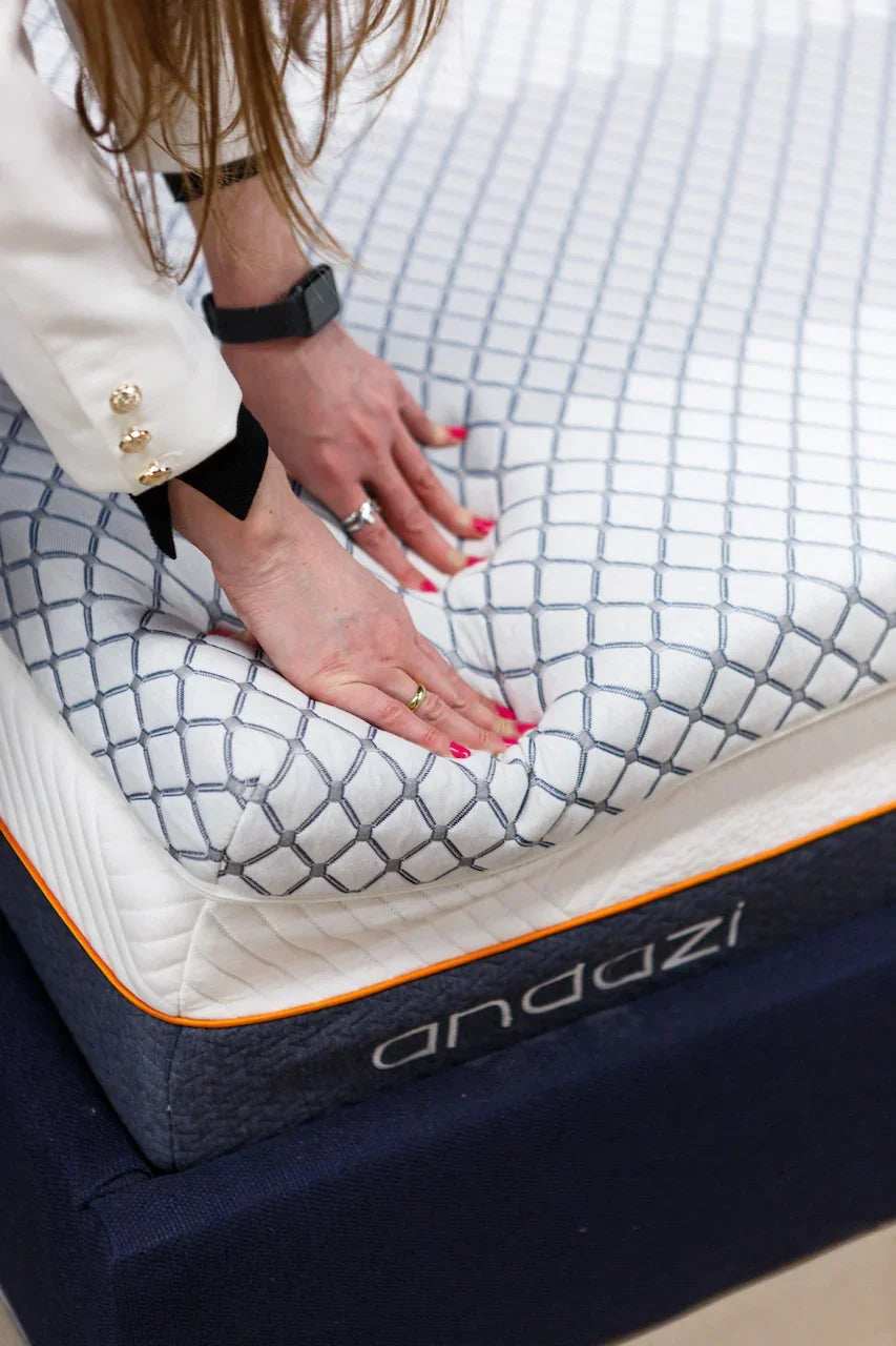 Hands pressing on a soft, patterned memory foam mattress with blue and white cover