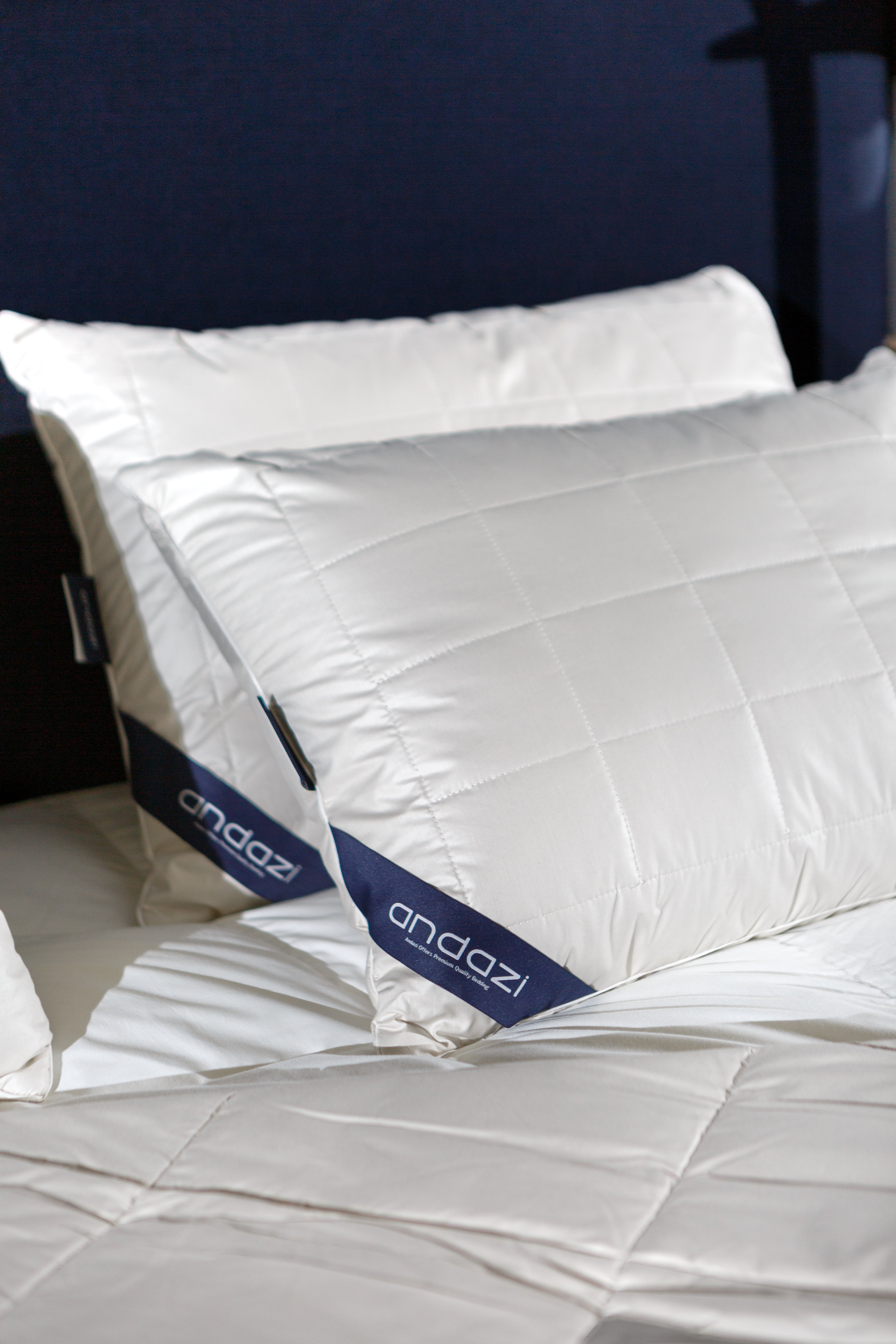 Premium white pillows with quilted pillowcases and bedding on a bed, close-up view