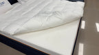 Modern white mattress with quilted bedding and pillow on a bed frame