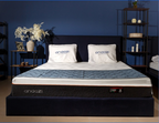 Modern bedroom with premium comfort mattress and pillows on a navy bed, blue wall background