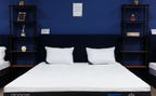Modern mattress with white cover and pillows in showroom, blue wall background, bedroom decor