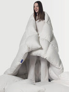 Woman wrapped in a large white comforter, cozy bedding and sleepwear setting