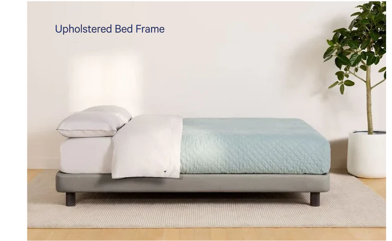Gray upholstered bed frame with light bedding in minimal modern bedroom