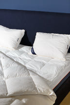 Modern bed with white pillows, mattress, and quilted duvet in a cozy bedroom setting