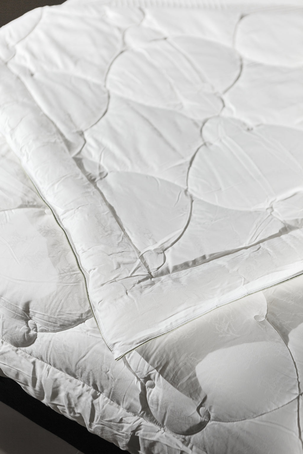 White quilted mattress protector spread on a bed, clean bedding, bedroom setting
