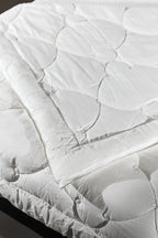 White quilted mattress protector spread on a bed, clean bedding, bedroom setting