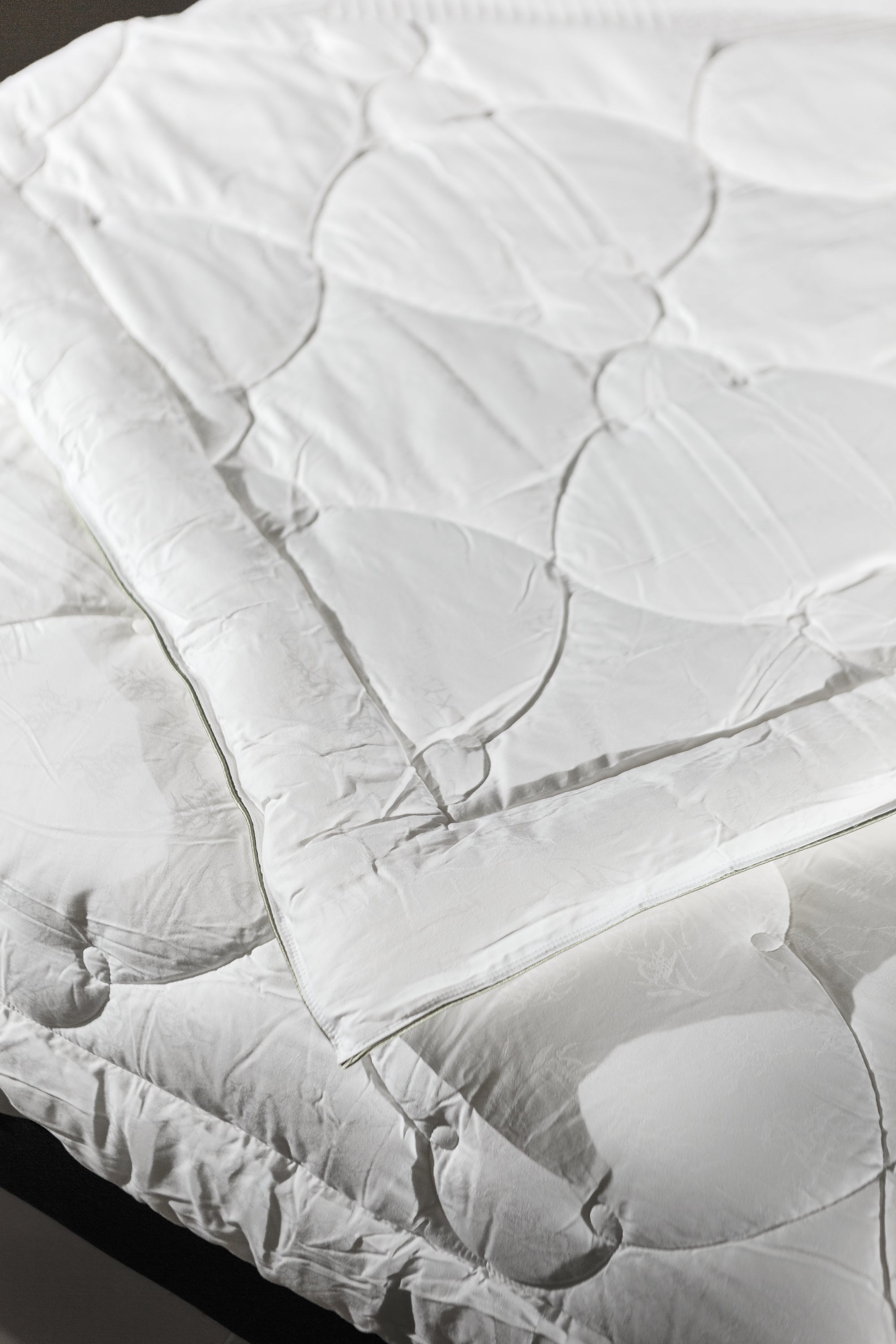 White quilted mattress protector spread on a bed, clean bedding, bedroom setting