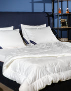 Modern bed with white mattress, fluffy comforter, and pillows in a cozy bedroom